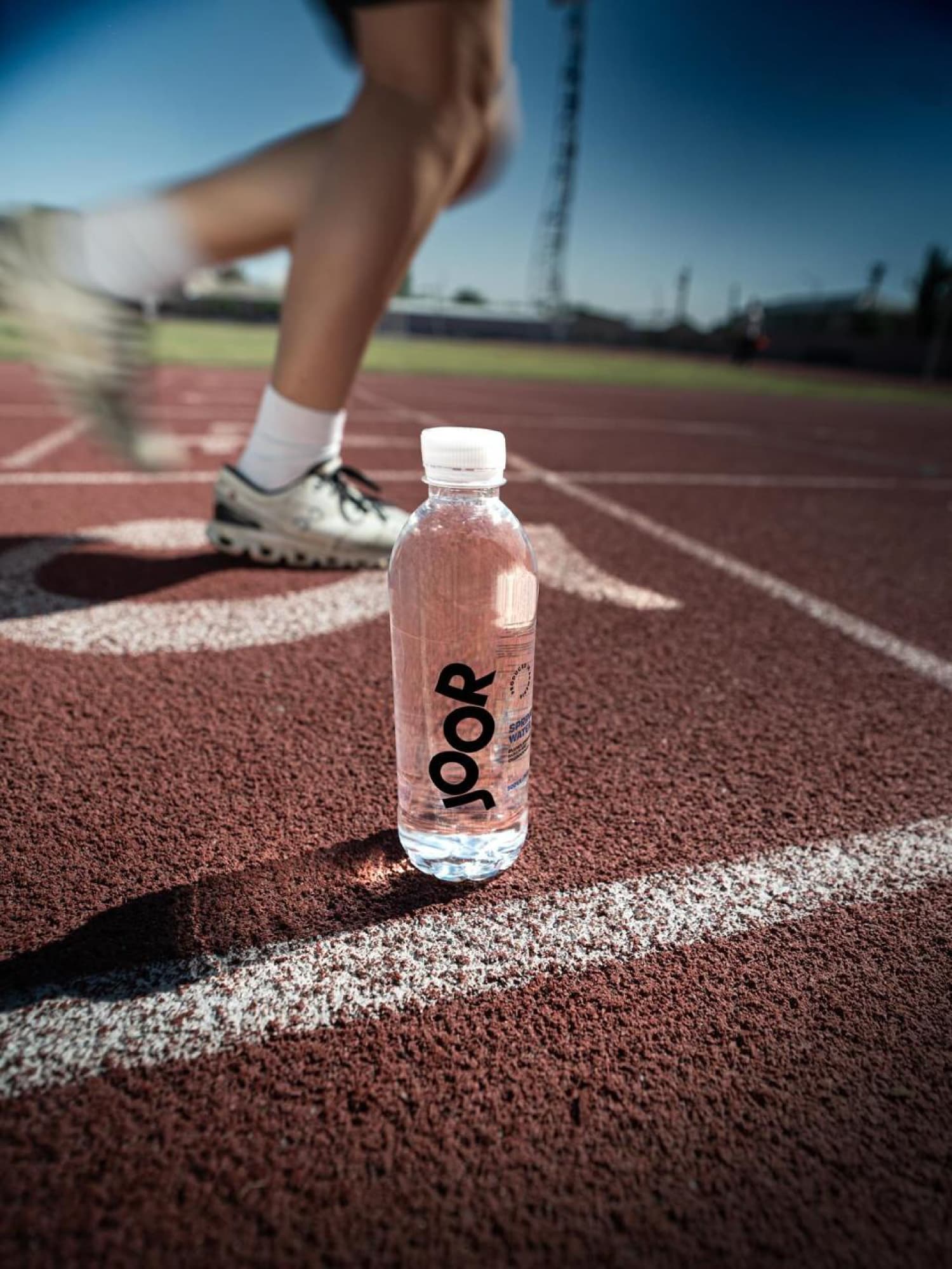 JOOR spring water bottle on an outdoor running track.